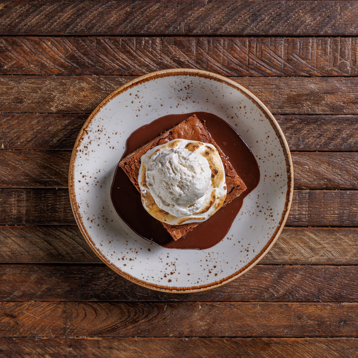 Dessert with ice cream and chocolate sauce on a rustic wooden table