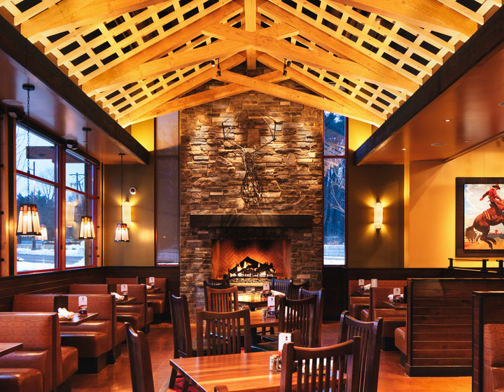 Dining area with wooden tables, chairs, and a stone fireplace.