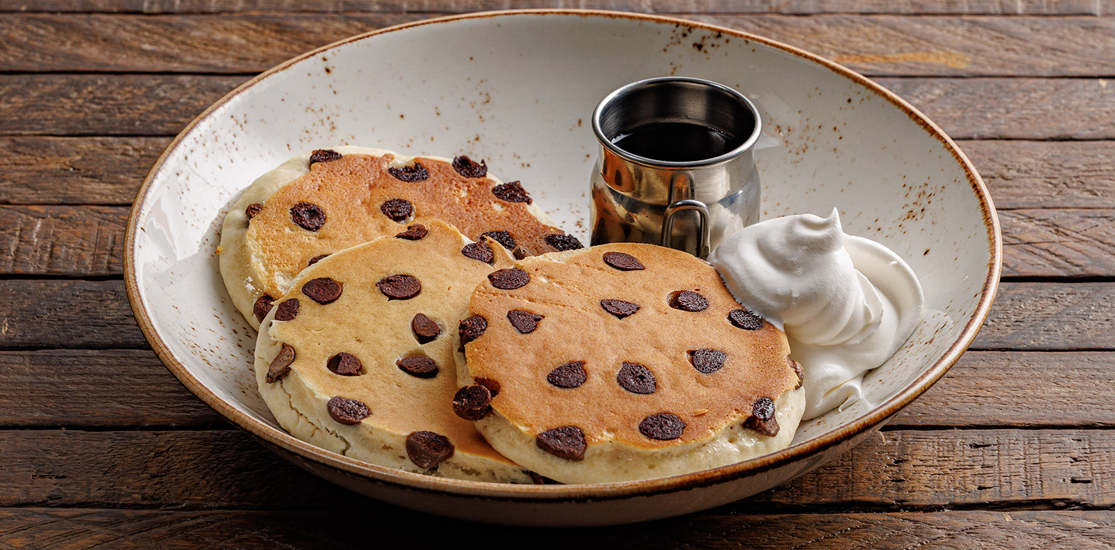 Chocolate chip pancakes with maple syrup and whipped cream